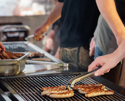 Gegrillte Bratwürste Grillmeister legt Bratwürste mit Zange auf den heißen Rost beim Zoiglbierfest.