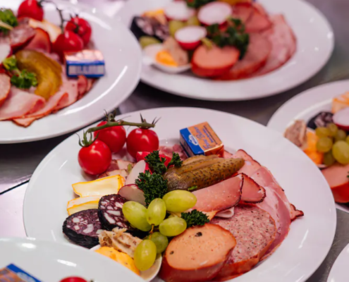 Brotzeitteller Mehrere Teller mit Zoiglfest-Brotzeit aus Wurst, Käse, Gemüse und Trauben aufgereiht
