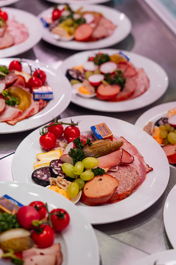 Brotzeitteller Mehrere Teller mit Zoiglfest-Brotzeit aus Wurst, Käse, Gemüse und Trauben aufgereiht