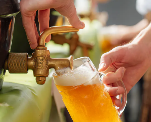 Frisch gezapftes Zoigl Hand zapft goldenes Zoiglbier aus Fasshahn in einen Maßkrug mit Schaumkrone.