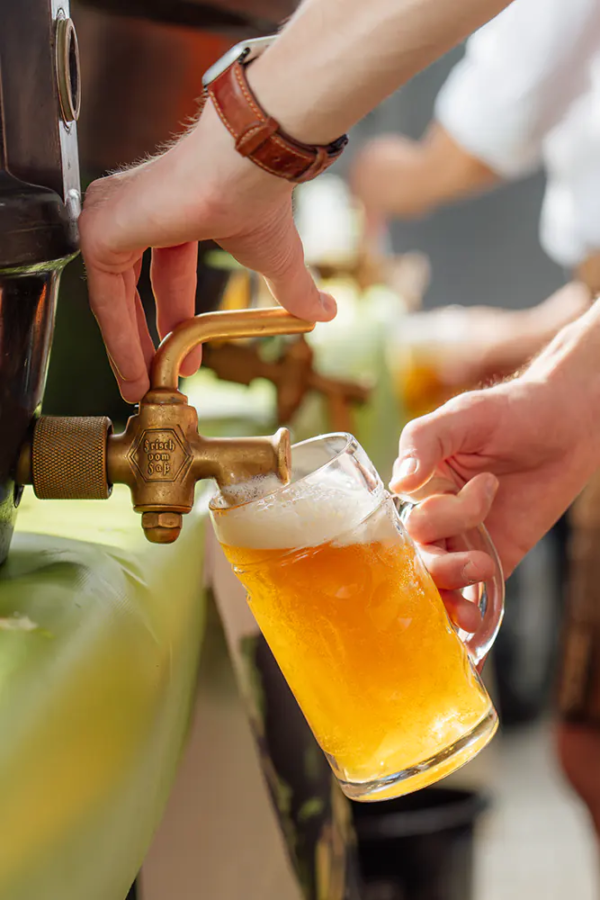 Frisch gezapftes Zoigl Hand zapft goldenes Zoiglbier aus Fasshahn in einen Maßkrug mit Schaumkrone.