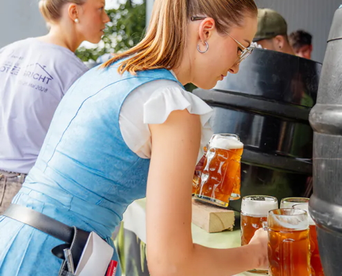 Nachschub holen Bedienung im blauen Dirndl holt frisch gezapfte Zoiglbier-Krüge von der Theke.