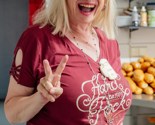Lisa Lachende Frau im roten Shirt zeigt beim Zoiglbierfest ein Victory-Zeichen in der Küche.