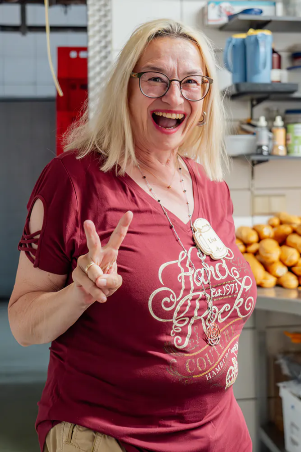 Lisa Lachende Frau im roten Shirt zeigt beim Zoiglbierfest ein Victory-Zeichen in der Küche.