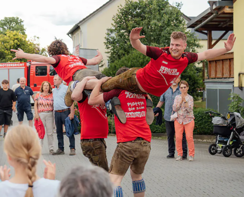 Neidaffer Plattclub Plattlergruppe in roten Shirts wirbeln zwei Tänzer waagerecht durch die Luft vor Publikum.
