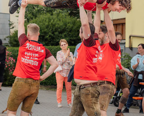 Neidaffer Plattlclub Plattlergruppe trägt einen Tänzer waagerecht durch die Luft über den Festplatz.