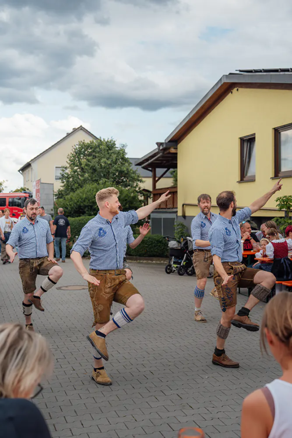 Plattler Männer in Lederhosen führen traditionellen Plattler-Tanz auf dem Hof des Zoiglbierfests auf.