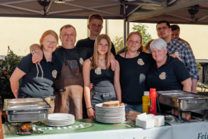 Ein Teil des Teams vom Piehlerhof steht lächelnd hinter der Brotzeit-Theke beim Zoiglbierfest.