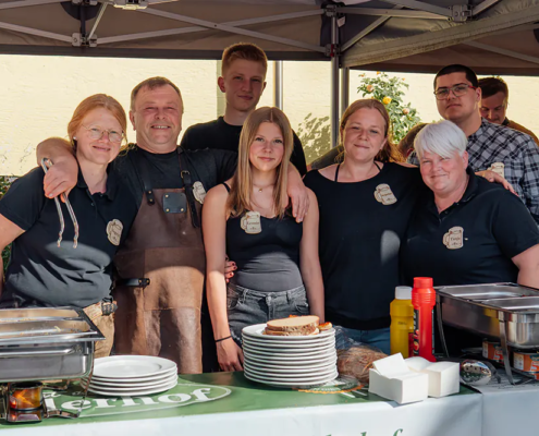 Verkostungsteam Ein Teil des Teams vom Piehlerhof steht lächelnd hinter der Brotzeit-Theke beim Zoiglbierfest.